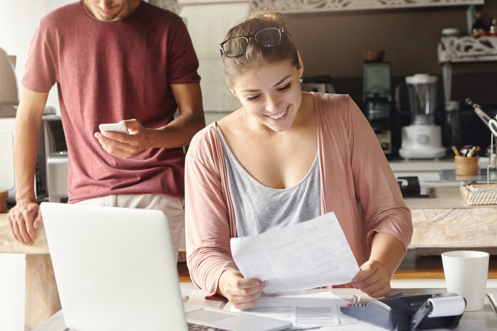 people looking at personal loans and finances smiling in kitchen.