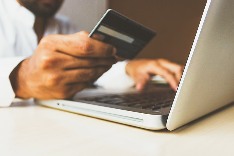 man holding credit card in front of computer