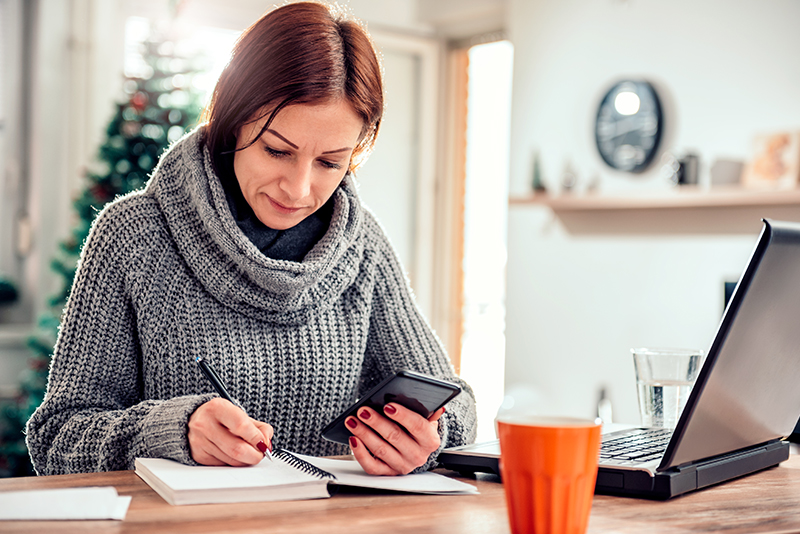 A woman writing in a notebook; pros and cons of refinancing your home