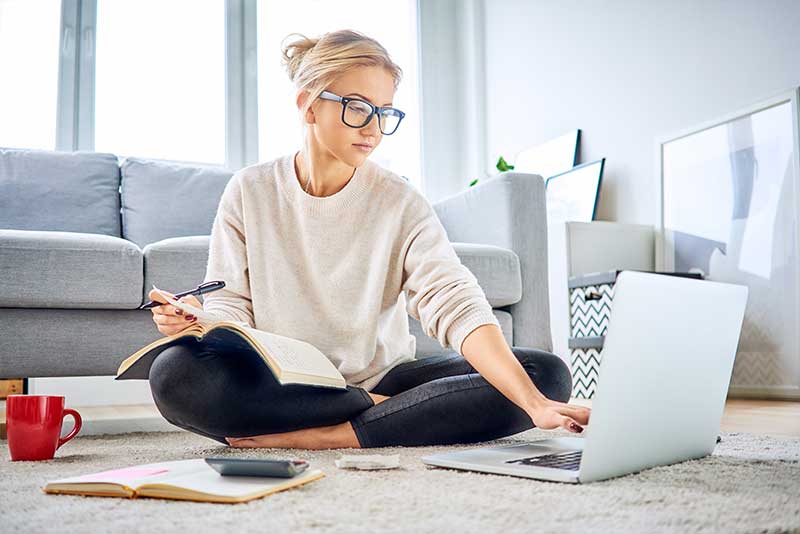 savings habits, woman using laptop on floor