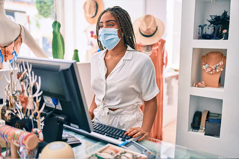 how to invest in your community, woman working retail wearing mask