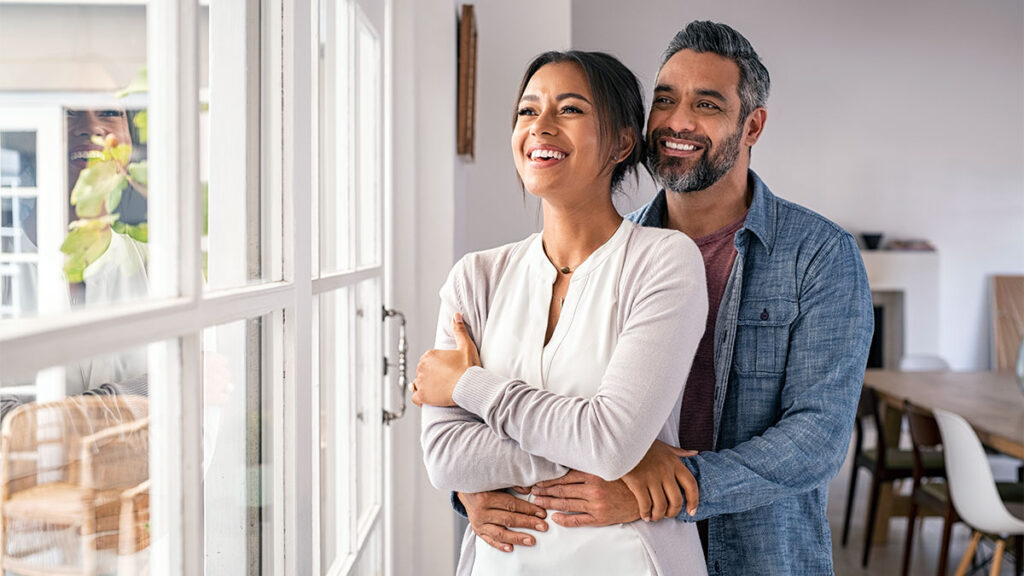 Couple hugging each other looking out a home window for a blog about securing your financial future