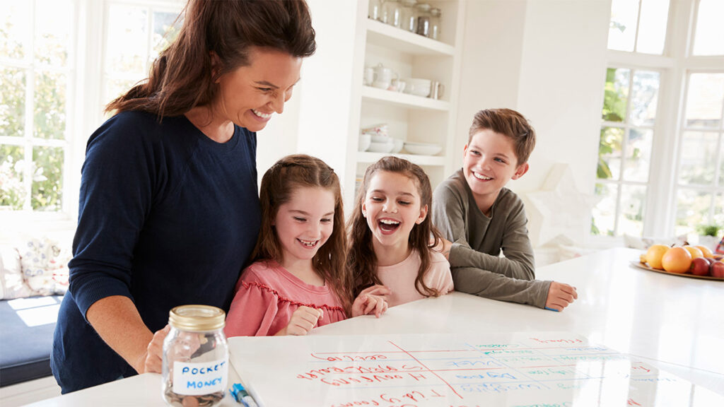 Mom with three young children at kitchen counter looking at papers for a blog discussing DEXSTA’s Youth Savings Club