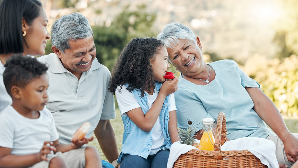 Family sitting in grass having picnic outside fora blog about credit union member benefits